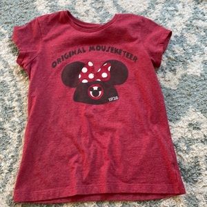 A red Disney shirt with letter on front.